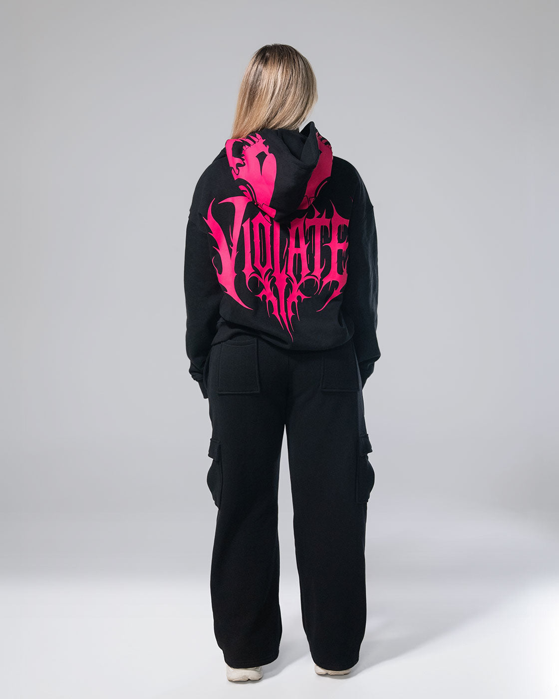 Photo of a girl in the black Royalty cargo sweats and hoodie, showing the back design of the items.