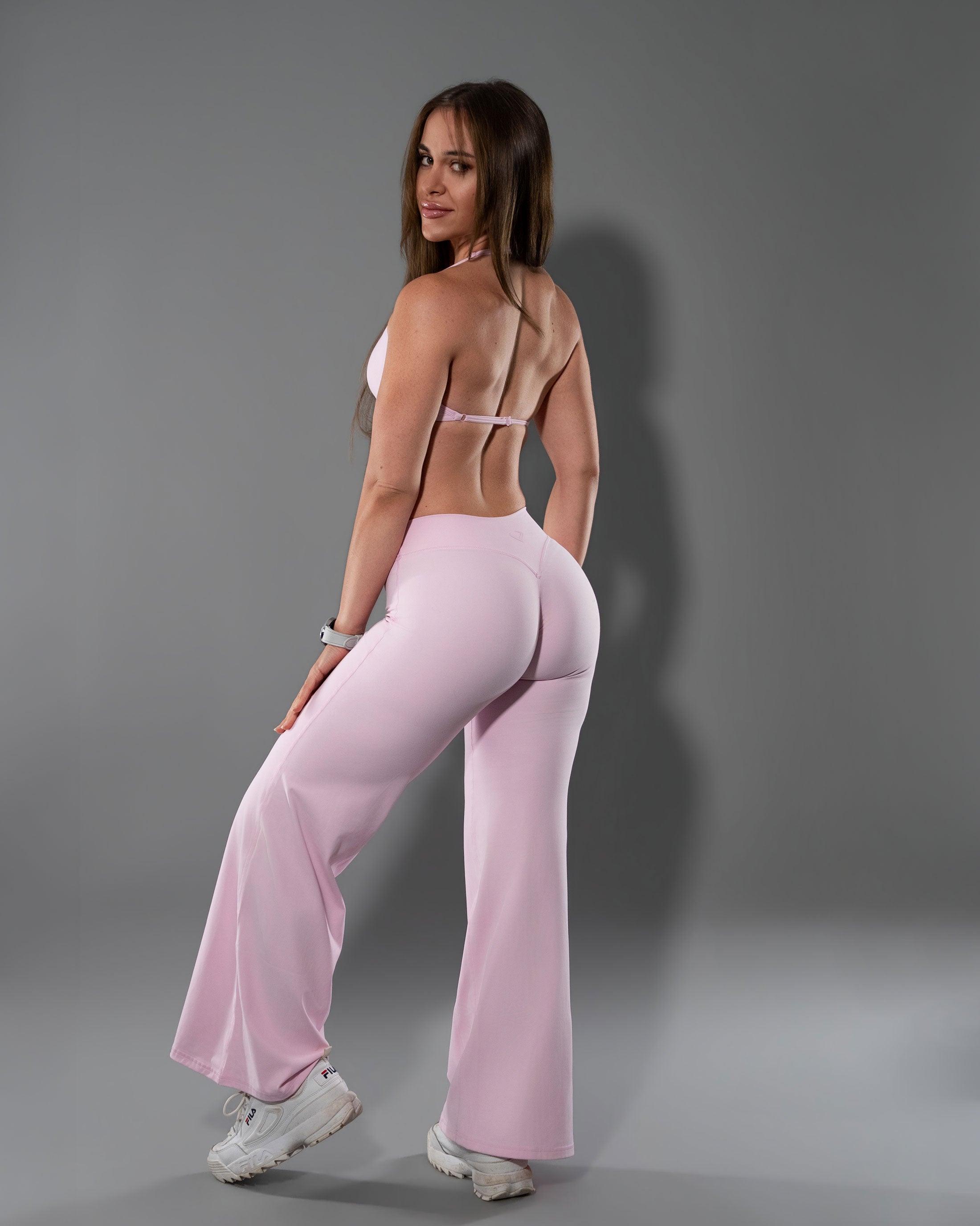Soft Pink Tempt flare leggings and halter top set photographed from behind